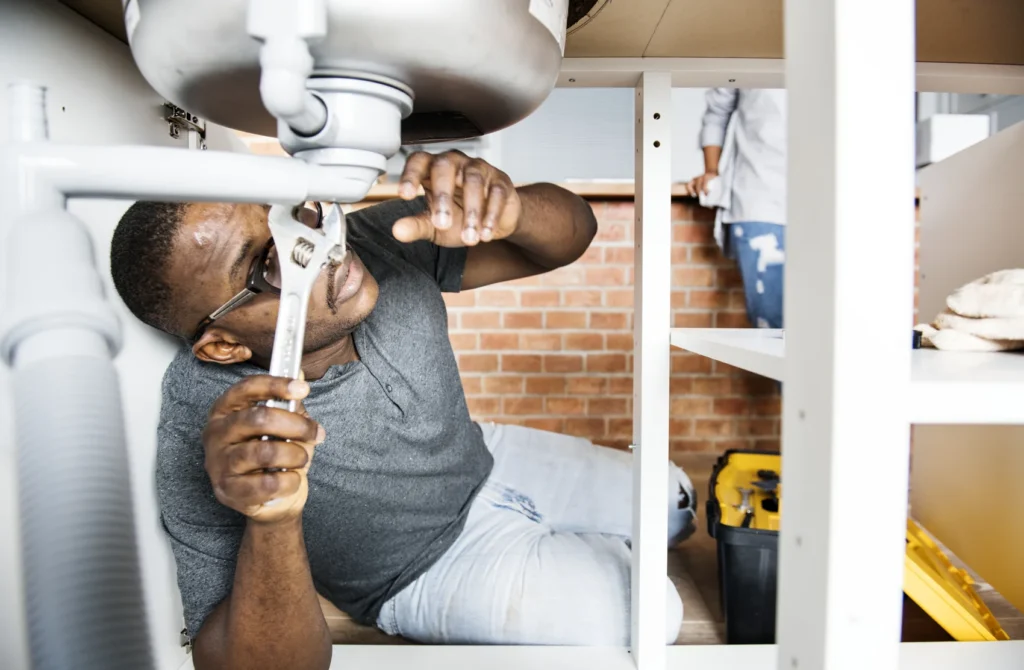 Plumber providing residential plumbing services at a home kitchen sink