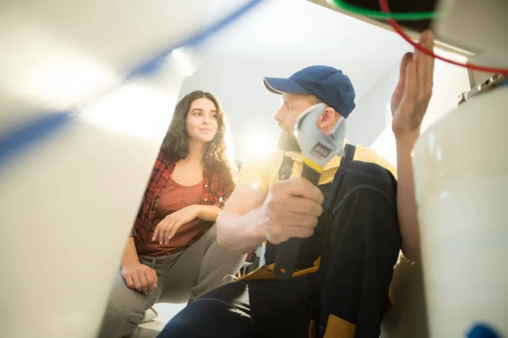Plumber talking with a woman about a repair under her sink