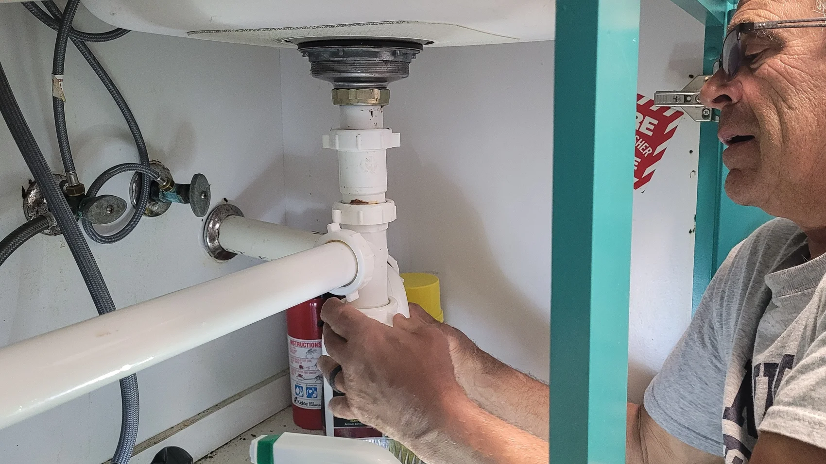 Plumber lying under a kitchen sink to repair the plumbing in a home