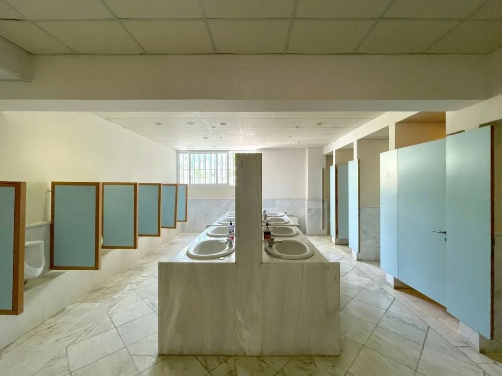 Commercial restroom with a row of sinks and partitioned stalls