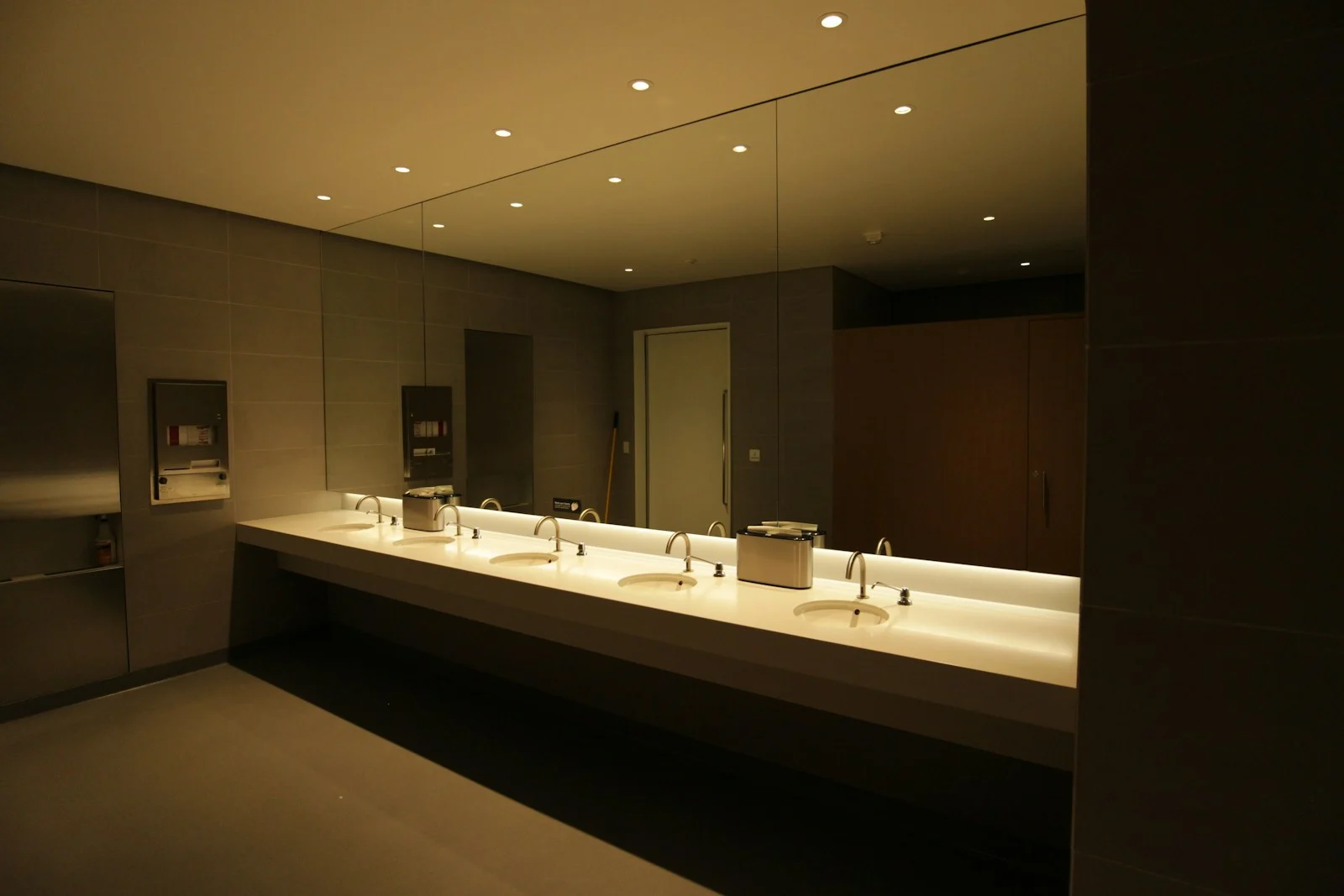 Commercial restroom vanity with a row of sinks and wall mirrors