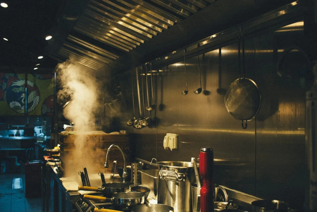 Steam rising over stockpots in a busy restaurant kitchen